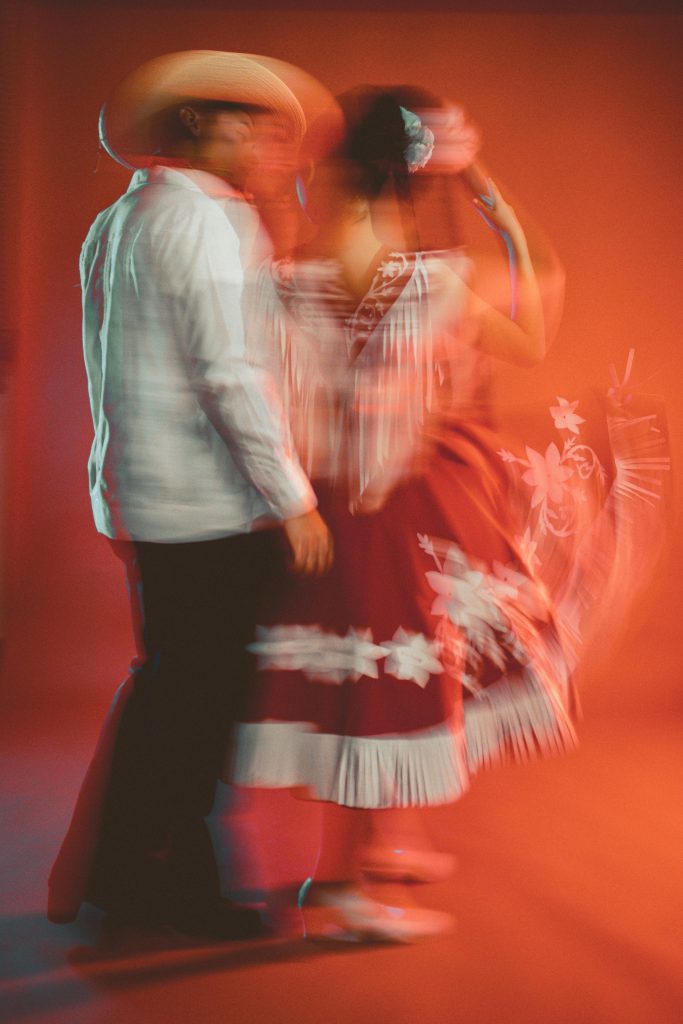 Vibrant blurred motion of a couple performing traditional Mexican dance in colorful attire.